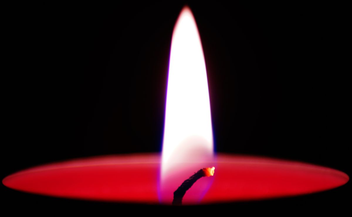 Close-up of a candle flame burning steadily above a wax pool, wick visible at the base