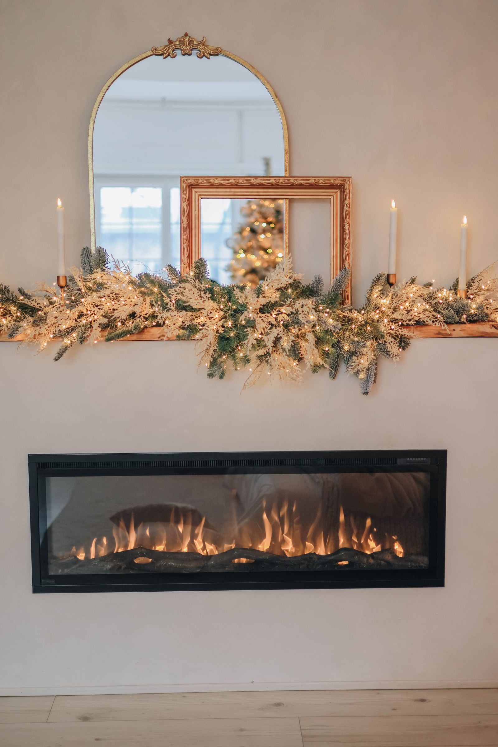 A beautifully decorated fireplace mantel for Christmas with candles and greenery