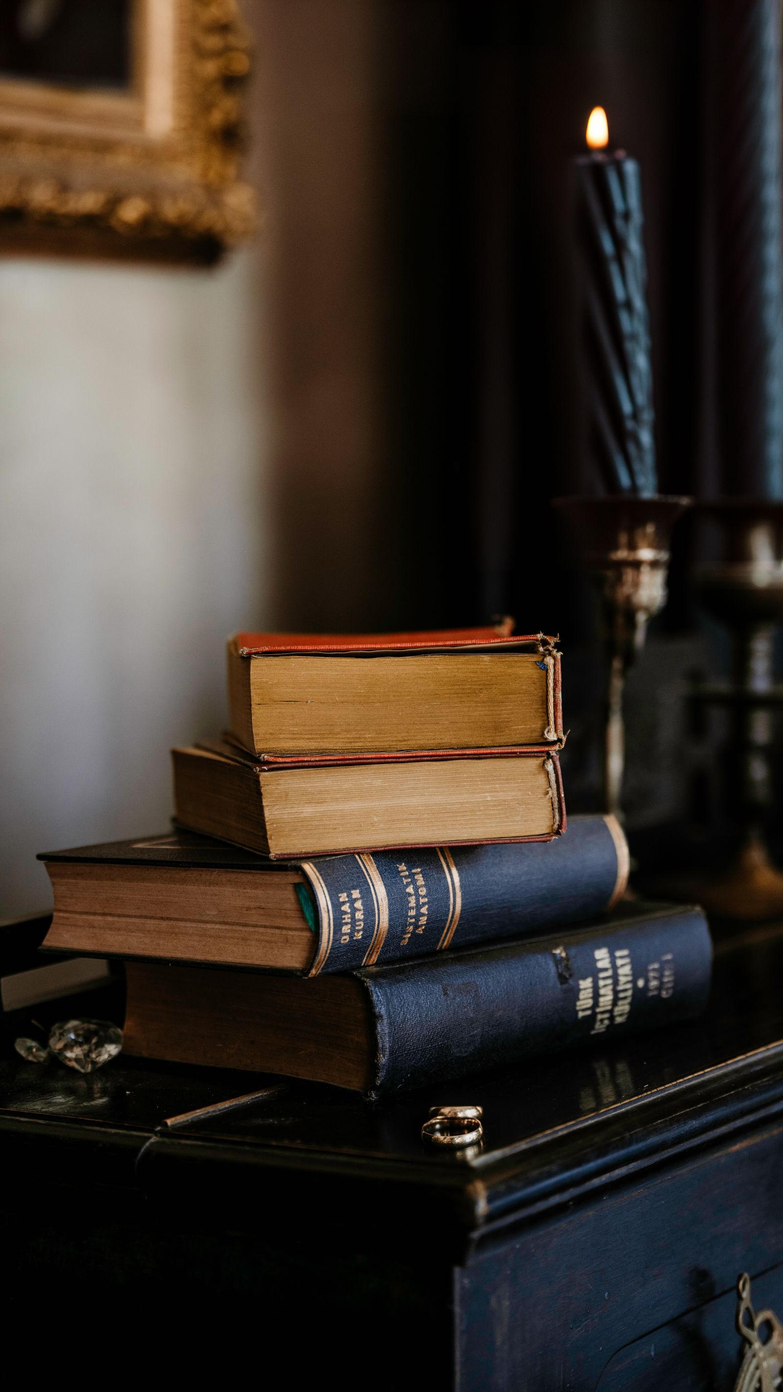 A stack of vintage books beside a lit candle