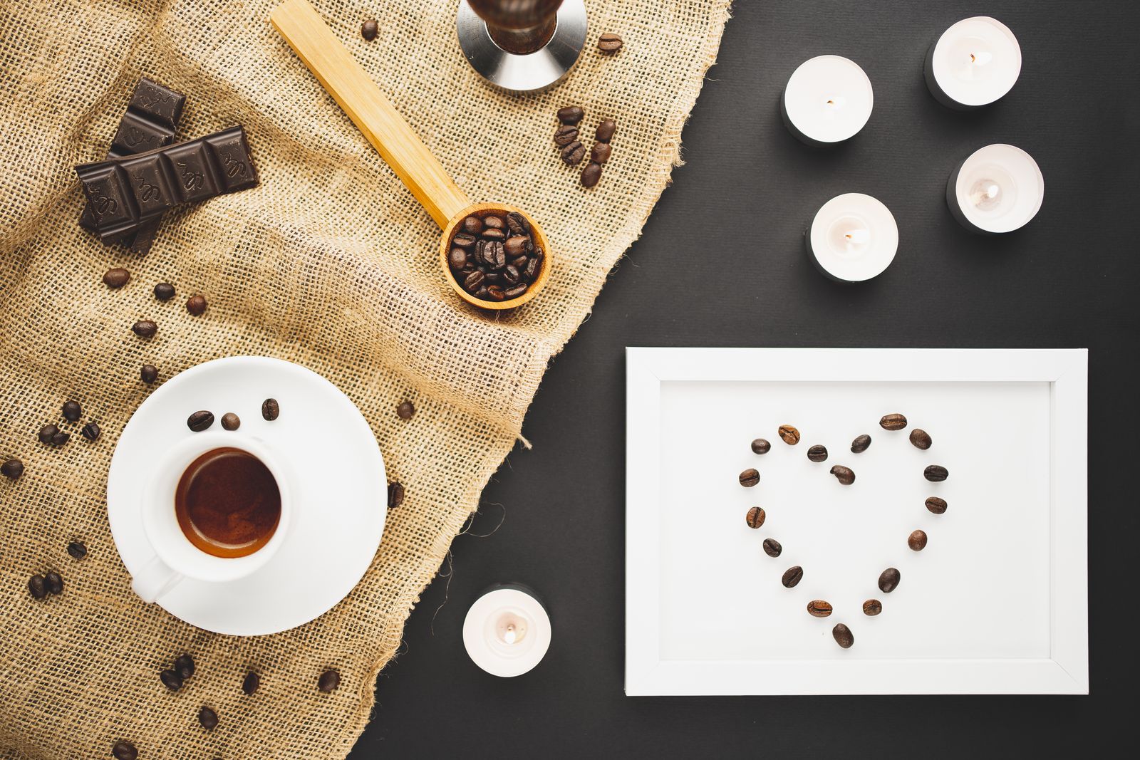 A flat lay of coffee, chocolate and candles on a jute cloth