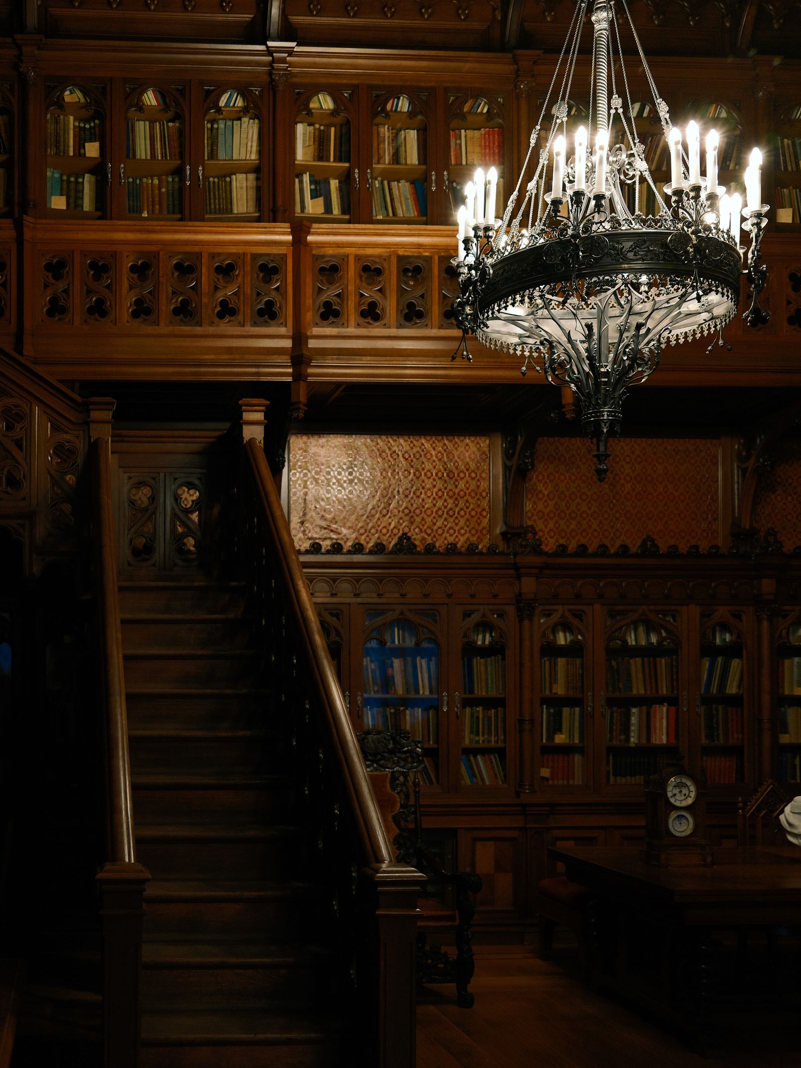 An elegant, dimly lit historical library with a chandelier