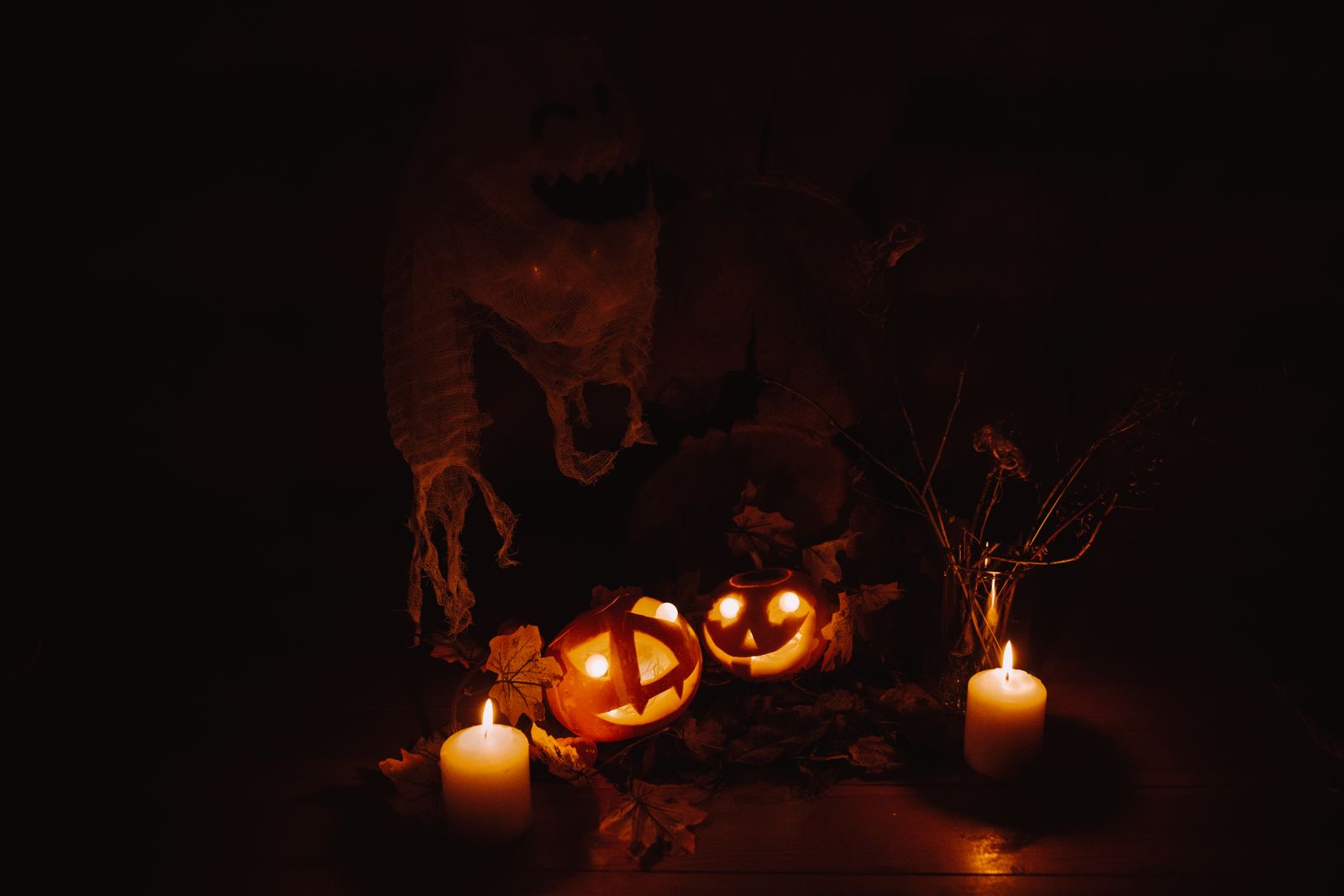 Lighted candles arranged near carved pumpkins