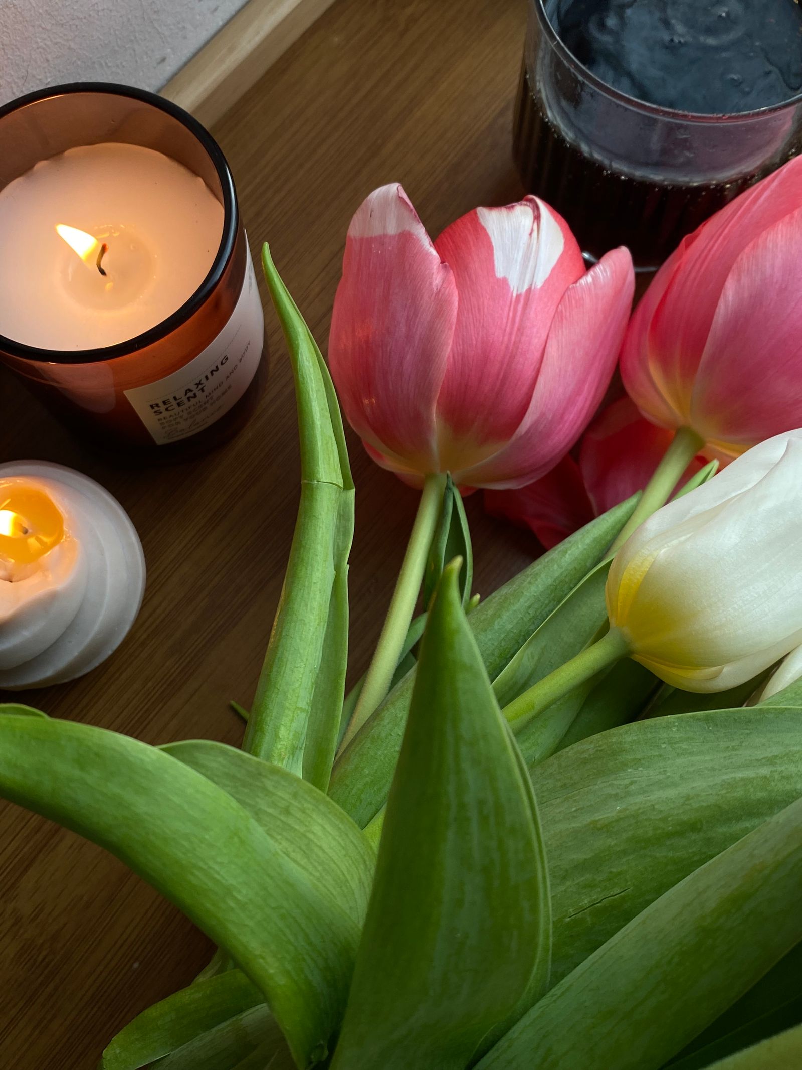 Blooming tulips beside lit candles on a wooden table